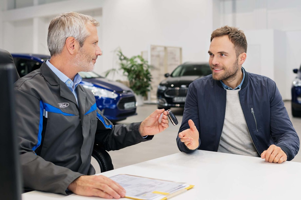 Twee mannen die tegenover elkaar zitten in een Ford dealerbedrijf