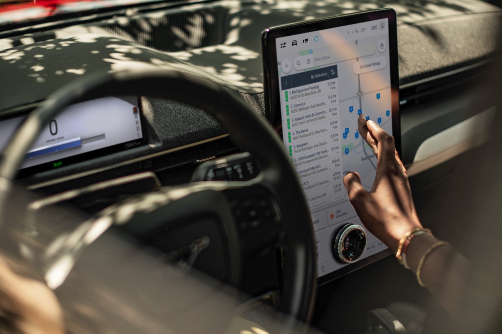 Een close-up van een vrouw in een Ford Mustang Mach-E die het grote SYNC-touchscreen gebruikt.