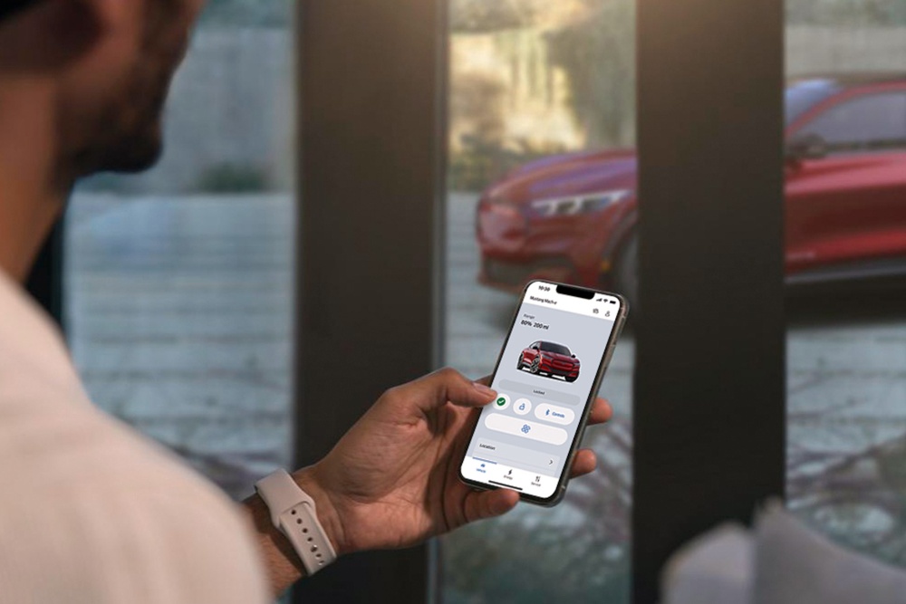 Een man die de instellingen van zijn gloednieuwe Ford Mustang Mach-E bekijkt met behulp van de voertuigcontrolefuncties op afstand in de FordPass-app