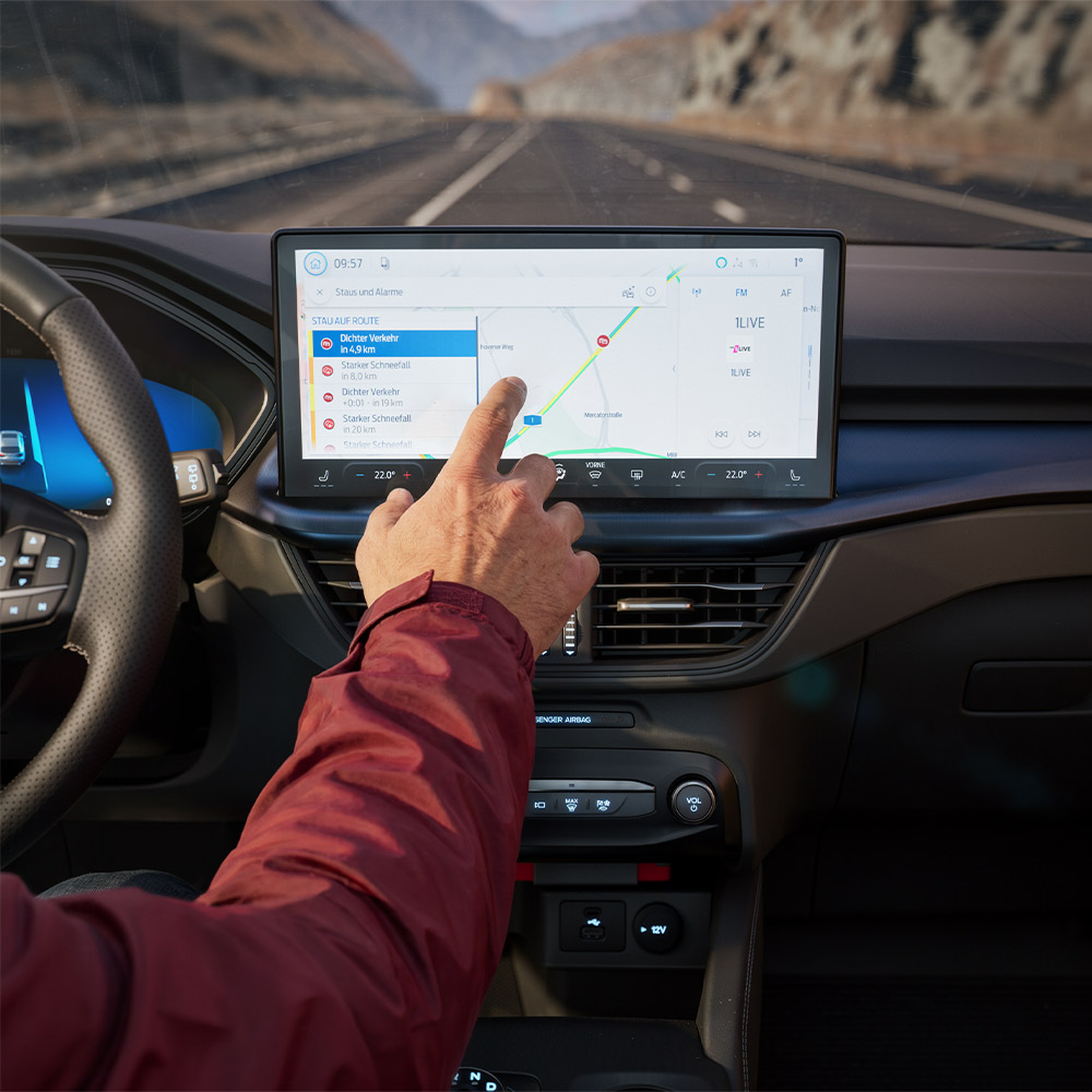 Een bestuurder gebruikt de Verbonden navigatie-functie op het digitale scherm van een Ford Kuga BlueCruise Edition.