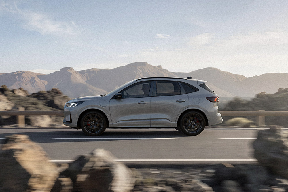 Zilverkleurige Ford Kuga die over een schilderachtige bergroute rijdt. 