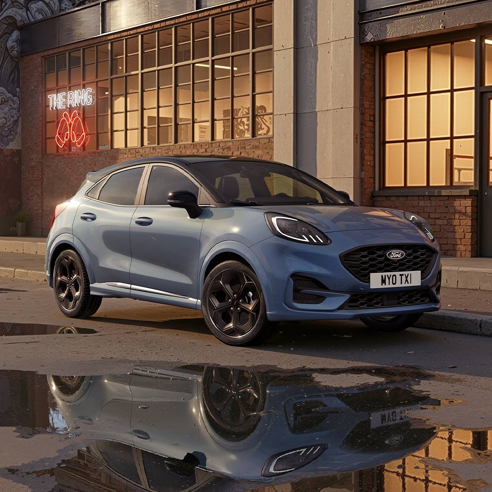 Een limited edition Vapour Blue Ford Puma staat 's nachts geparkeerd op een slecht verlichte stadsweg.