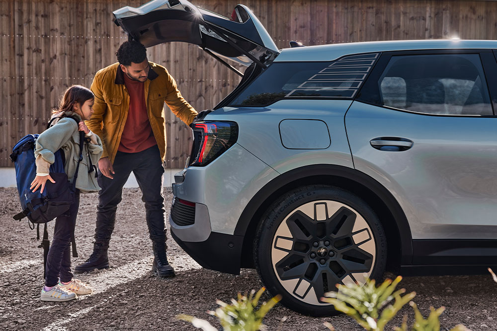 Een vader en dochter die de kofferbak van een zilveren Ford Explorer® inladen.