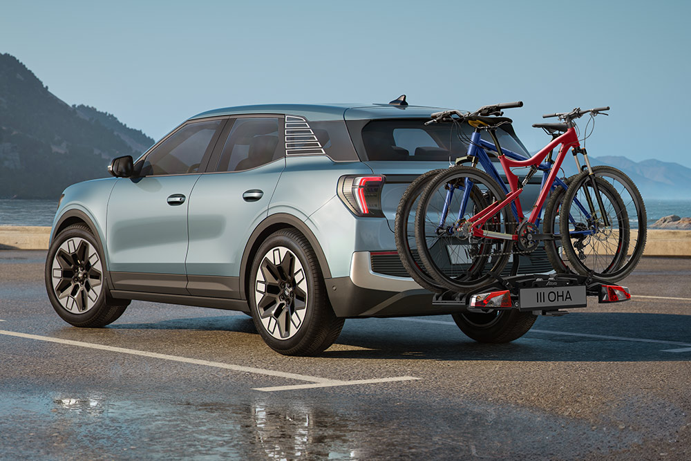 Blauwe Ford Explorer rijdend over een onverharde weg, met dwarsbalken, een fietsendrager op het dak en twee fietsen op het dak gemonteerd.