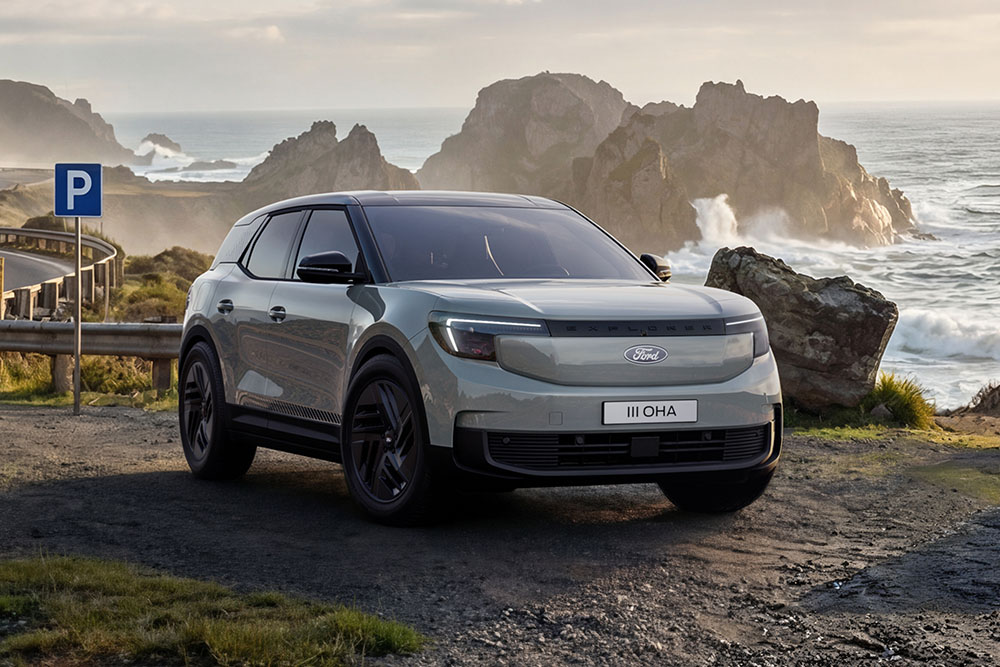 Een zilverkleurige Ford Explorer® Collection die geparkeerd staat op een weg langs een rotsachtige kustlijn.