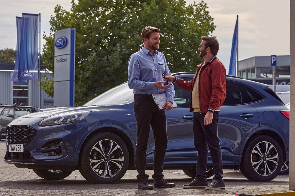 Vrouw die de sleutels van een Ford-voertuig overhandigt aan een servicemonteur