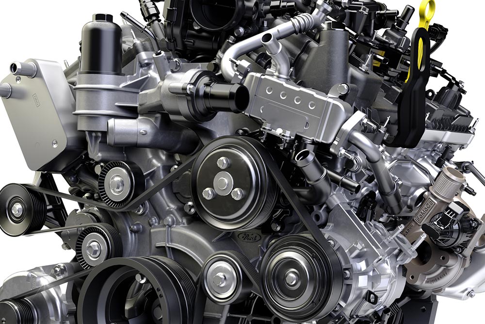 Close-up van een voertuigmotor met talrijke aandrijfriemen, riemschijven en mechanische onderdelen.