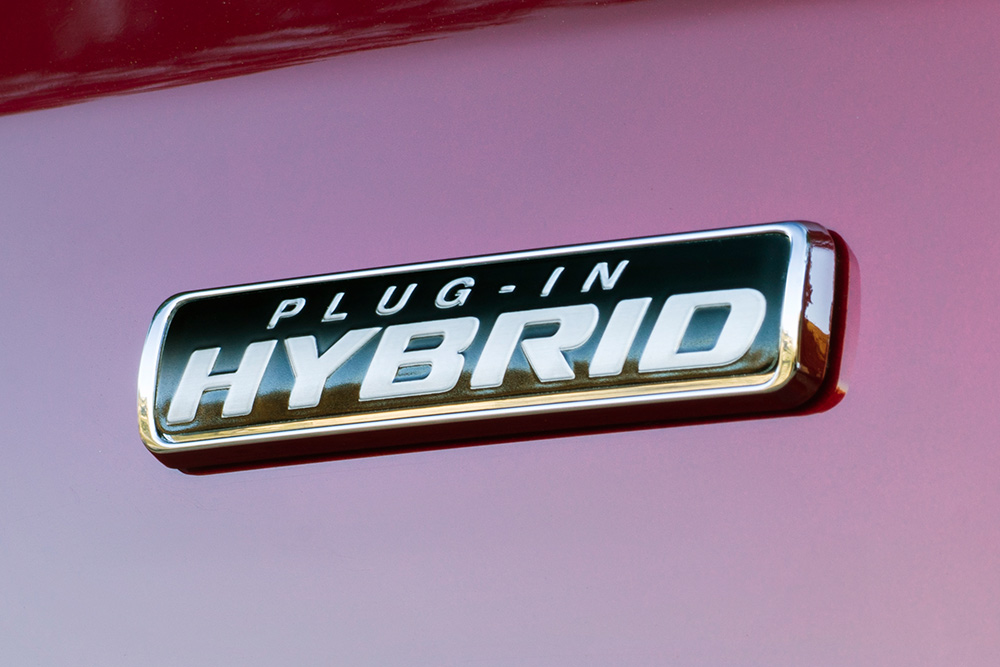 Close-up van het Plug-in Hybrid-embleem op een rode Ford Transit Custom.