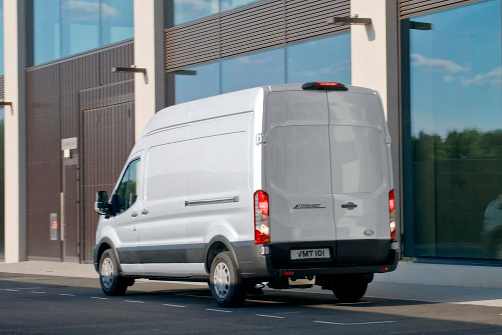 Achteraanzicht van een witte Ford Transit-bestelwagen die op straat geparkeerd staat.