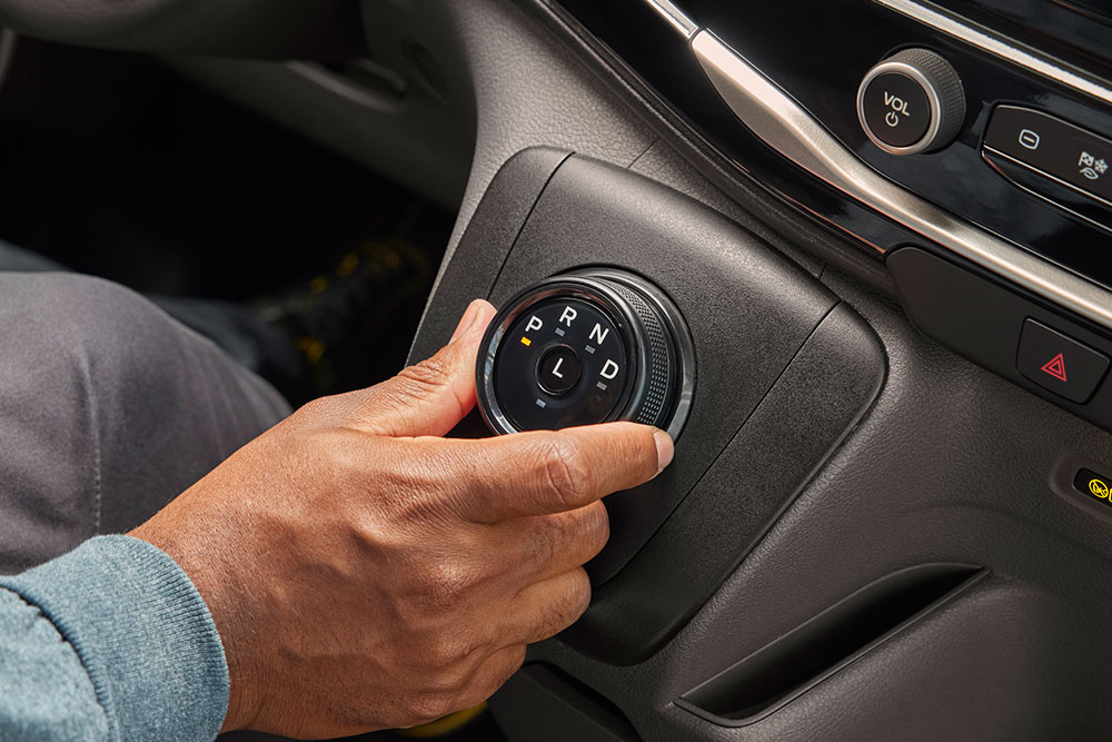 Close-up van een hand die aan de versnellingsknop van een Ford E-Transit elektrische bestelwagen draait.