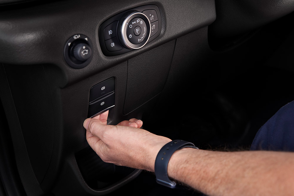 Close-up van een hand die op een knop drukt op het dashboard van een Ford E-Transit elektrische bestelwagen.