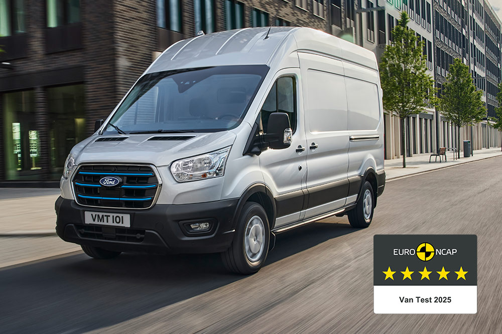 Zilveren Ford E-Transit elektrische bestelwagen die op een weg rijdt met een “Gold 2022 Commercial Van Safety”-badge.