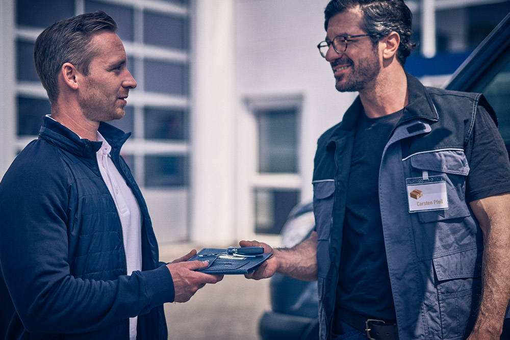 Man die een tablet aan een andere man geeft voor een Ford Transit-bestelwagen.