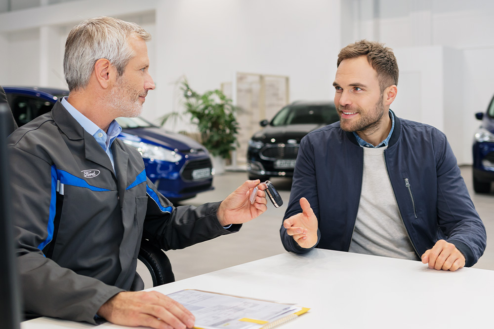 Een Ford-adviseur overhandigt een klant de sleutels terwijl de verschillende Ford-financieringsmogelijkheden worden besproken. 