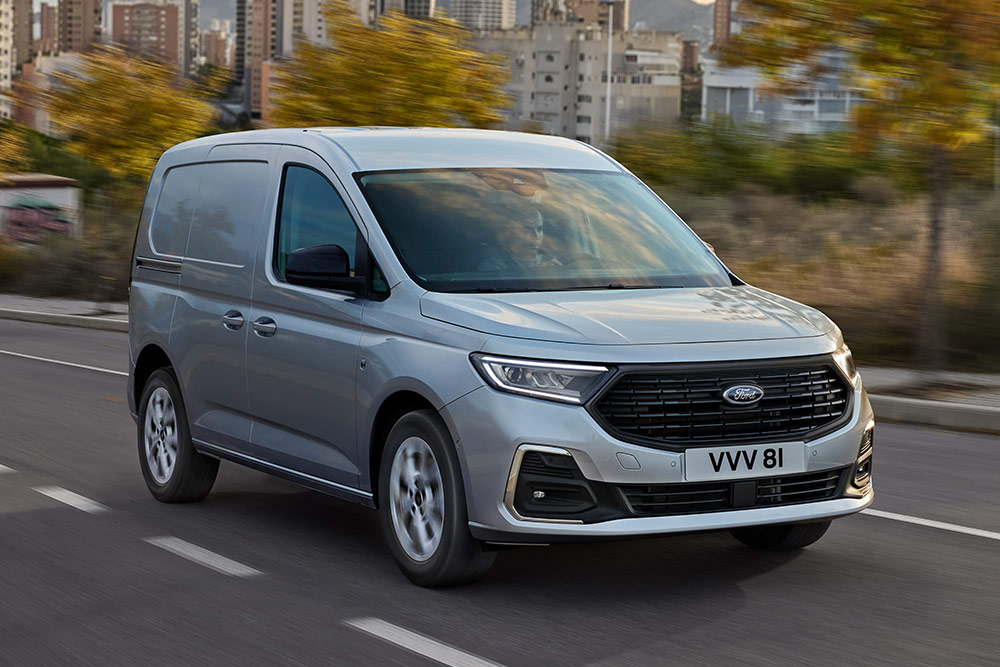 Ford Transit Connect driving in a city, showing chrome exterior fog lamp surrounds and automatic headlights.