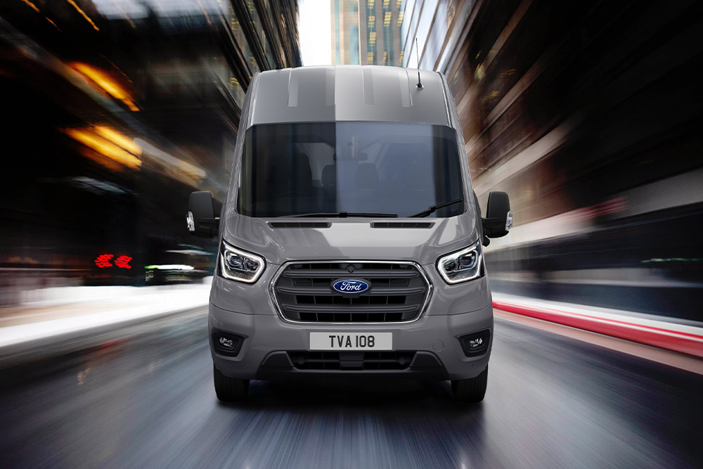 Vooraanzicht van een Ford Transit-bestelwagen die door de stad rijdt.