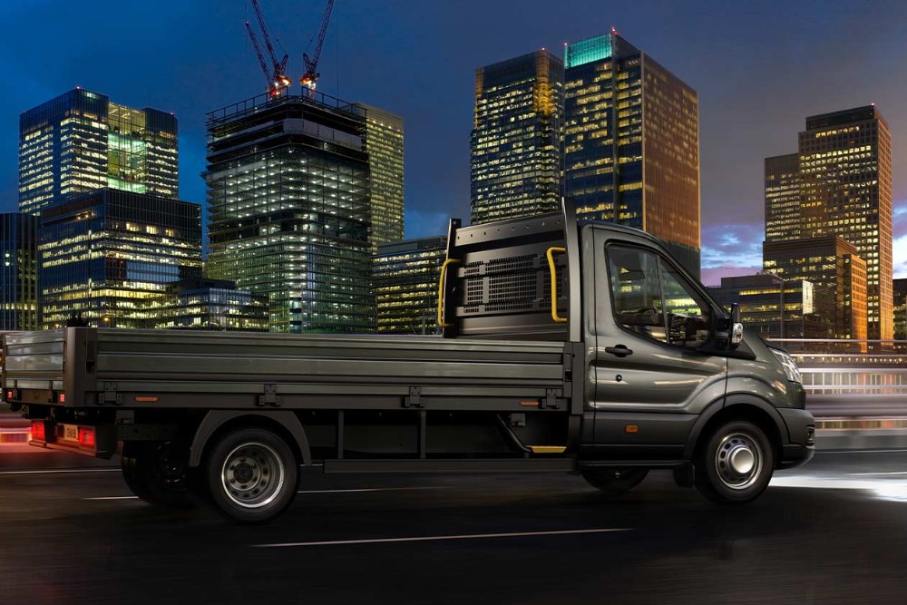 Een Ford Transit-chassis met cabine die ’s nachts over een stadsweg rijdt. 