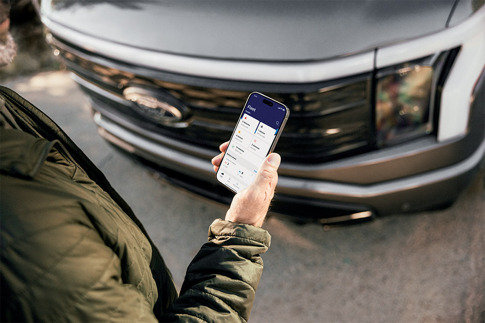 Een man kijkt op zijn smartphone voor een Ford Ranger.