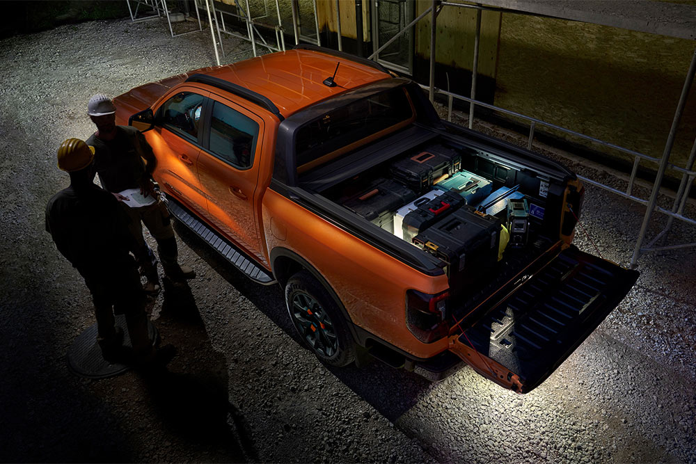 Bovenaanzicht van een oranje Ford Ranger Wildtrak bij nacht, met zoneverlichting aan de buitenzijde.