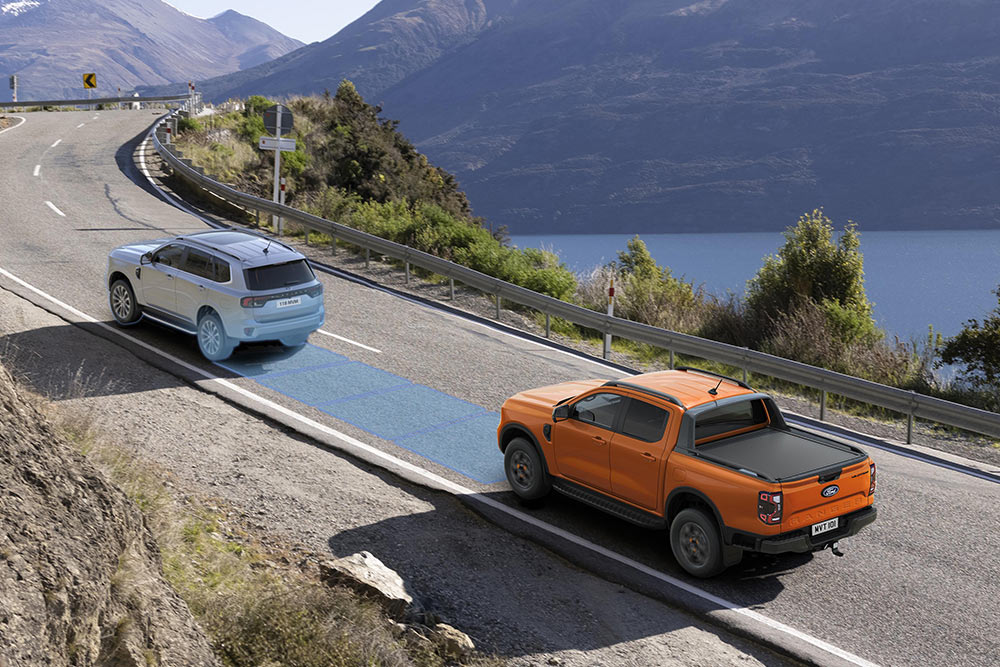 Een oranje Ford Ranger op een kustweg, met het geavanceerde rijhulpsysteem ingeschakeld. 
