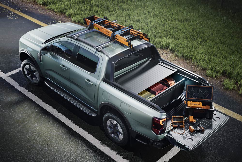 Een grijze Ford Ranger pick-up truck is van achteren te zien, met open laadbak, gereedschap en een imperiaal. 