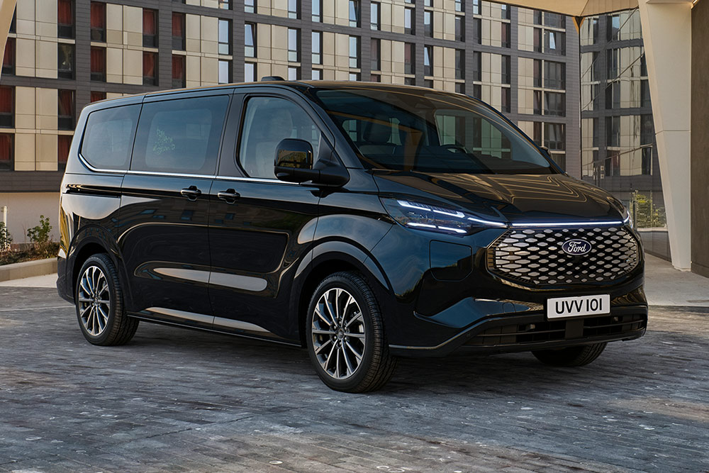 Zwarte Ford Pro Transit geparkeerd voor een modern gebouw.