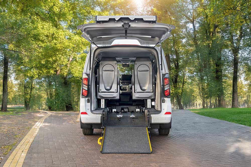 Achteraanzicht van een witte Ford Transit Custom met open achterklep en uitgeschoven rolstoelhelling.