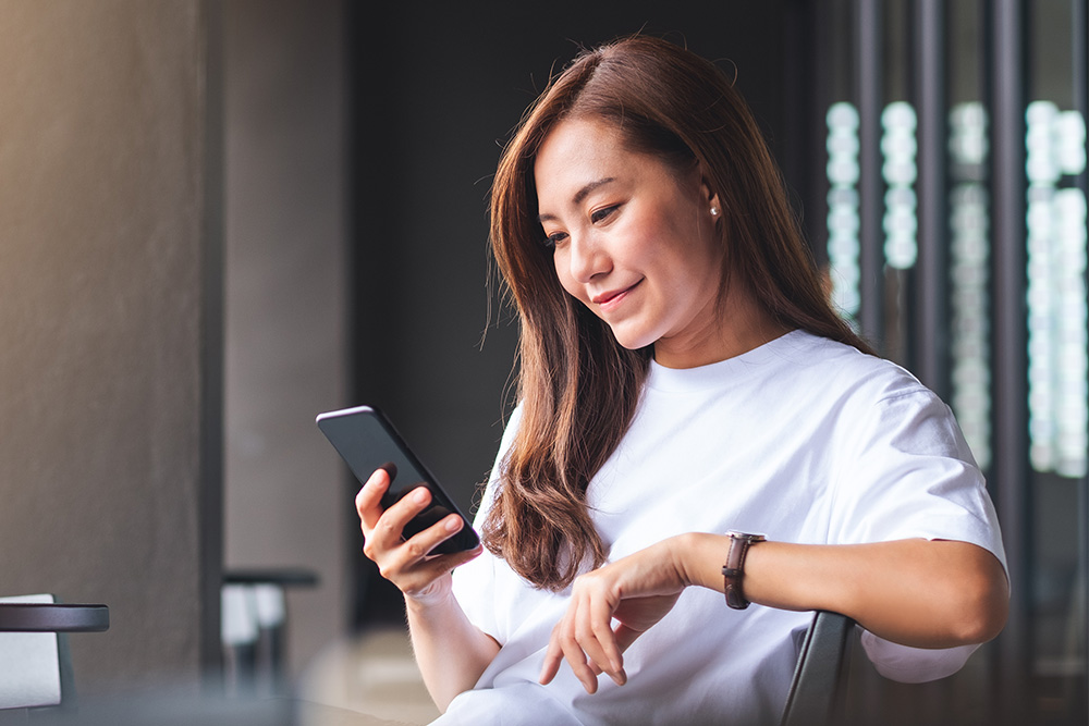  Vrouw controleert realtime meldingen van de FordPass-app op haar mobiele apparaat.