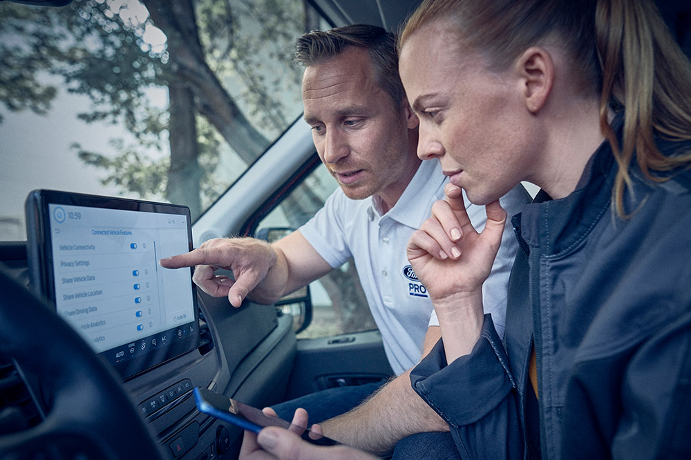 Wagenparkbeheerders zitten in een bedrijfswagen en bekijken data op het Ford Sync scherm.