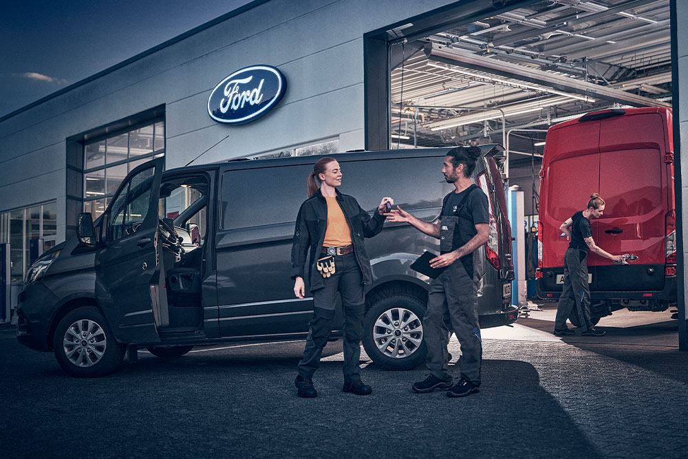  Klant en Ford-technicus wisselen sleutels uit voor een bestelwagen voor een Ford Dealer.