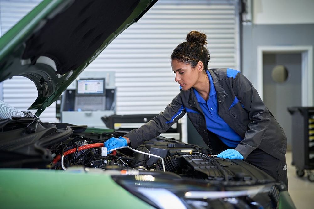 Een Ford-monteur inspecteert in een garage een automotor met de motorkap open.